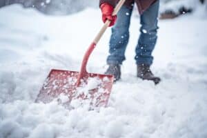 a person shovels snow with a red shovel